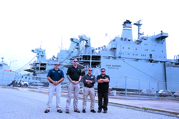 four men in front of naval ship