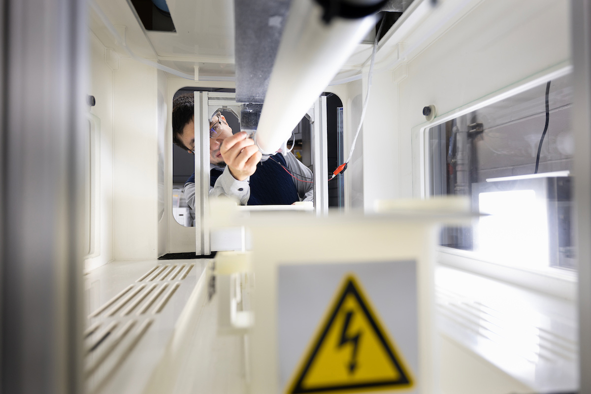 Yury Salkovskiy, Ph.D., works in the Materials Lab taking off cloth created by laying material over a cylindrical tube using an electrical field.