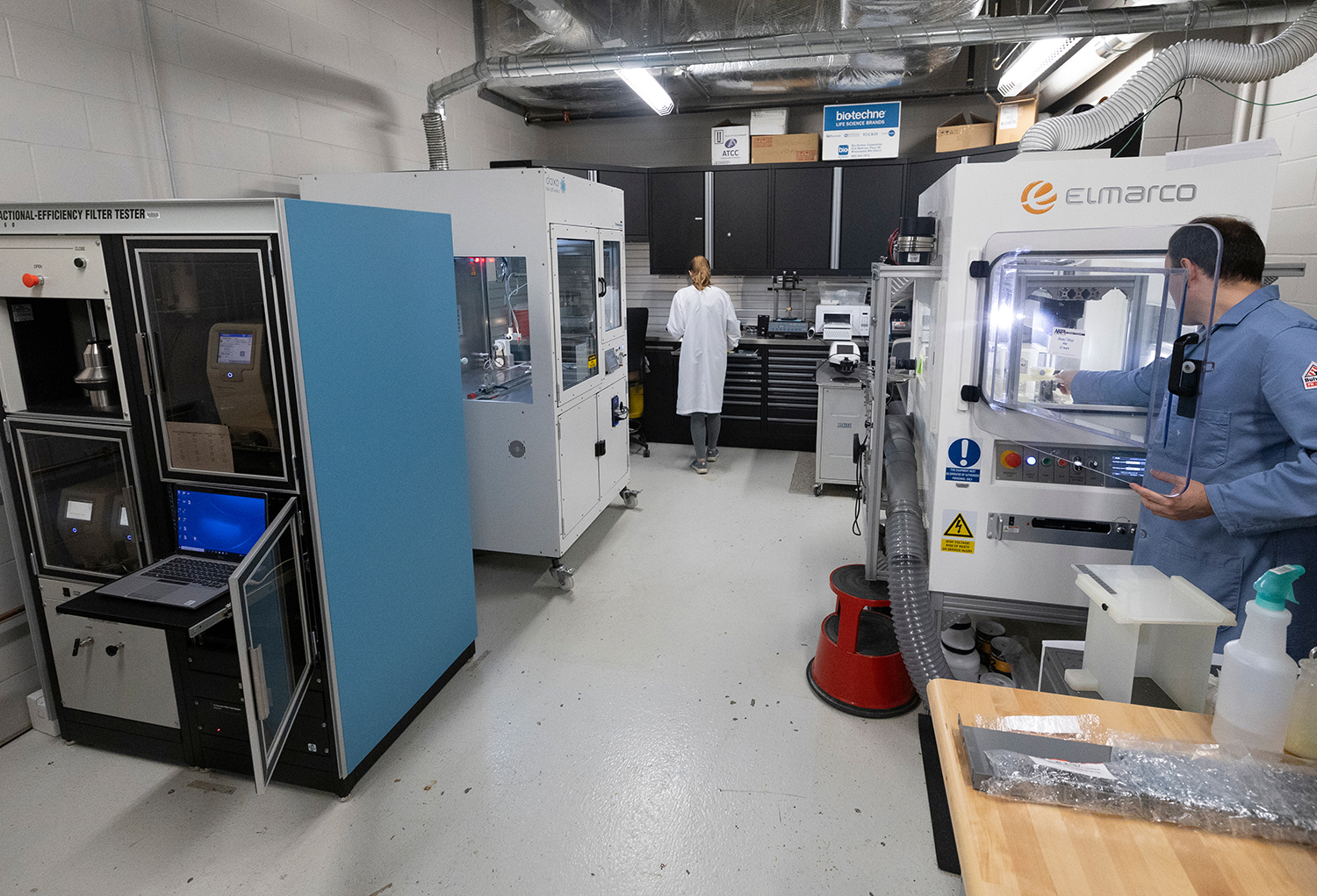 Two scientists standing in foreground and background of lab around large biomechanics equipment