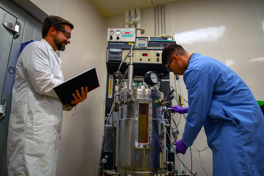 male scientists in lab coats operate device in laboratory