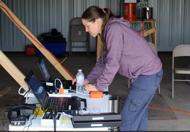 female scientist at field testing site sitting at computer