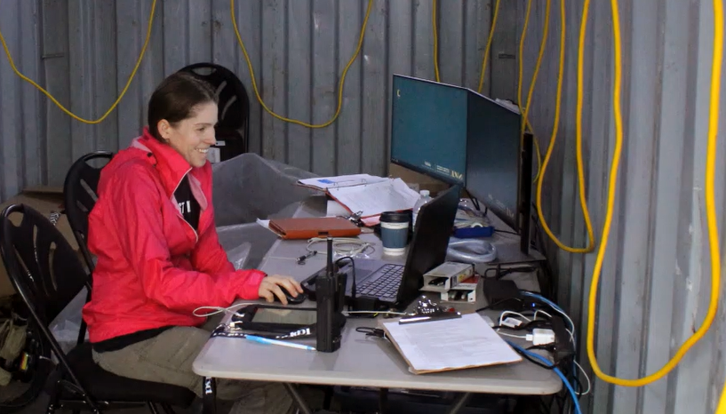 female scientist at field testing site sitting at computer