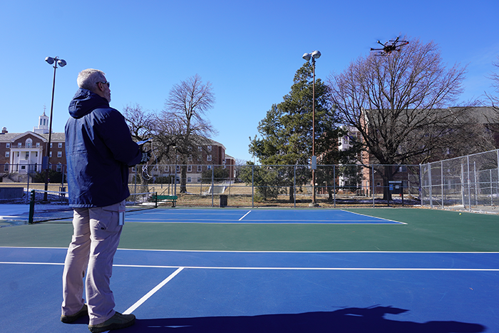 David Roberts flying a drone over tennis court at University of Nebraska–Lincoln