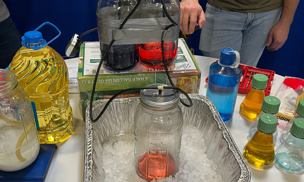 The student is combining multiple chemical compounds and colling the mixture in an ice bath.