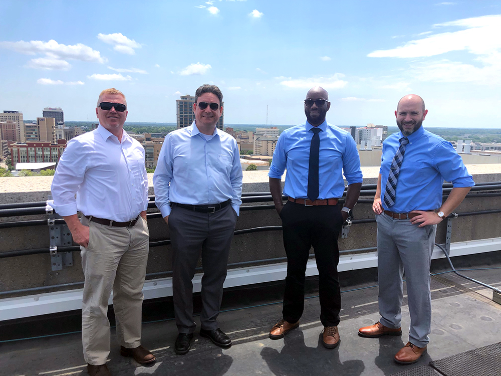 group photo of grant team on top of roof with Lincoln, NE, downtown skyline behind them