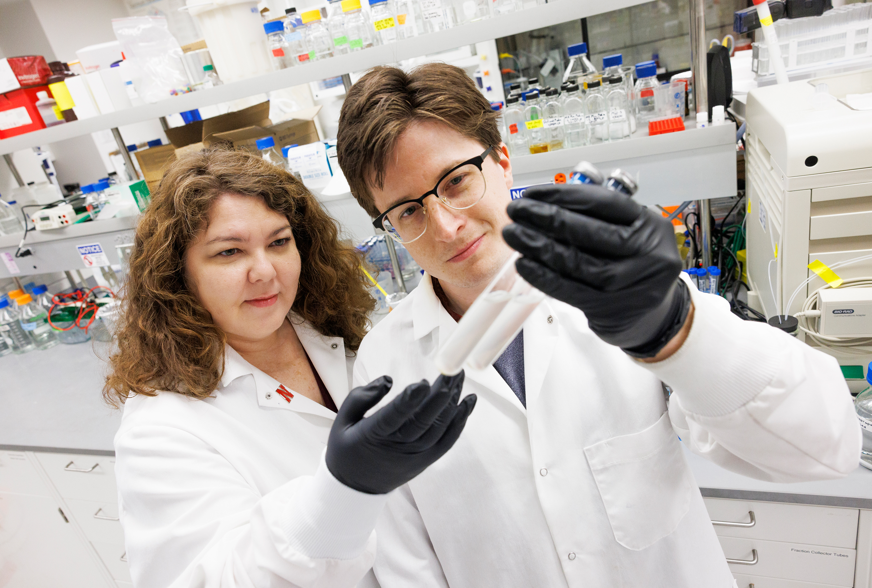 Female and male researchers hold of beaker to examine contents