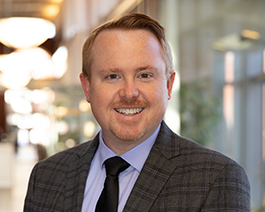 A man in a suit and tie is smiling.