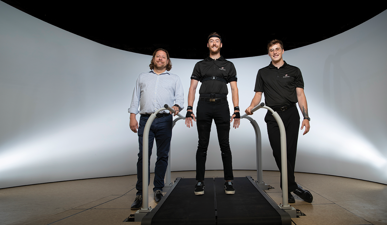 three men standing on or next to testing treadmill