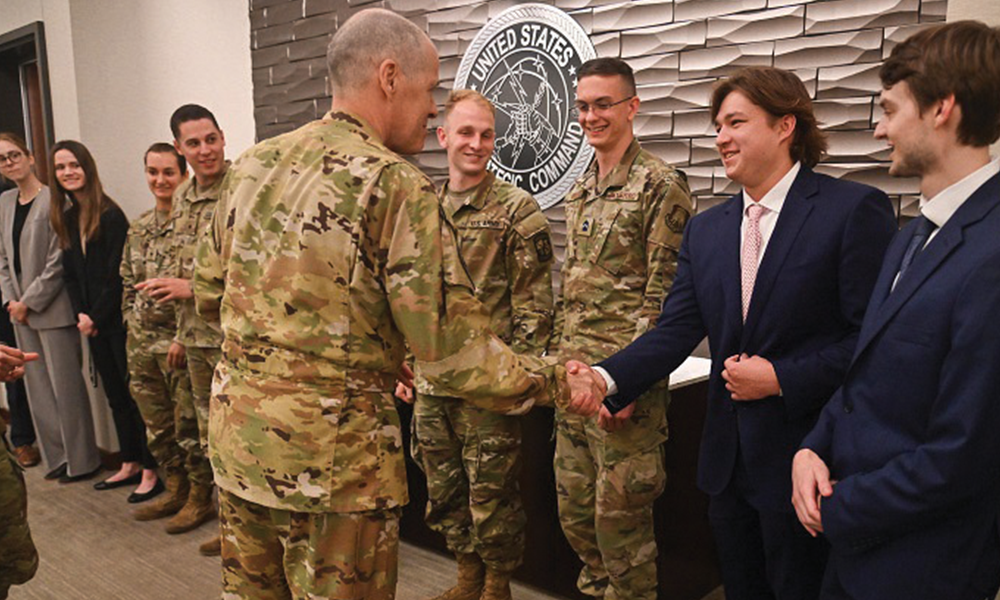 general in uniform shakes hand with student in front of STRATCOM seal