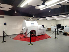 Large MRI scanner in a modern medical imaging room, cordoned off with stanchions and set on a red platform in a clinical facility
