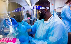 Scientist at the bench in full PPE