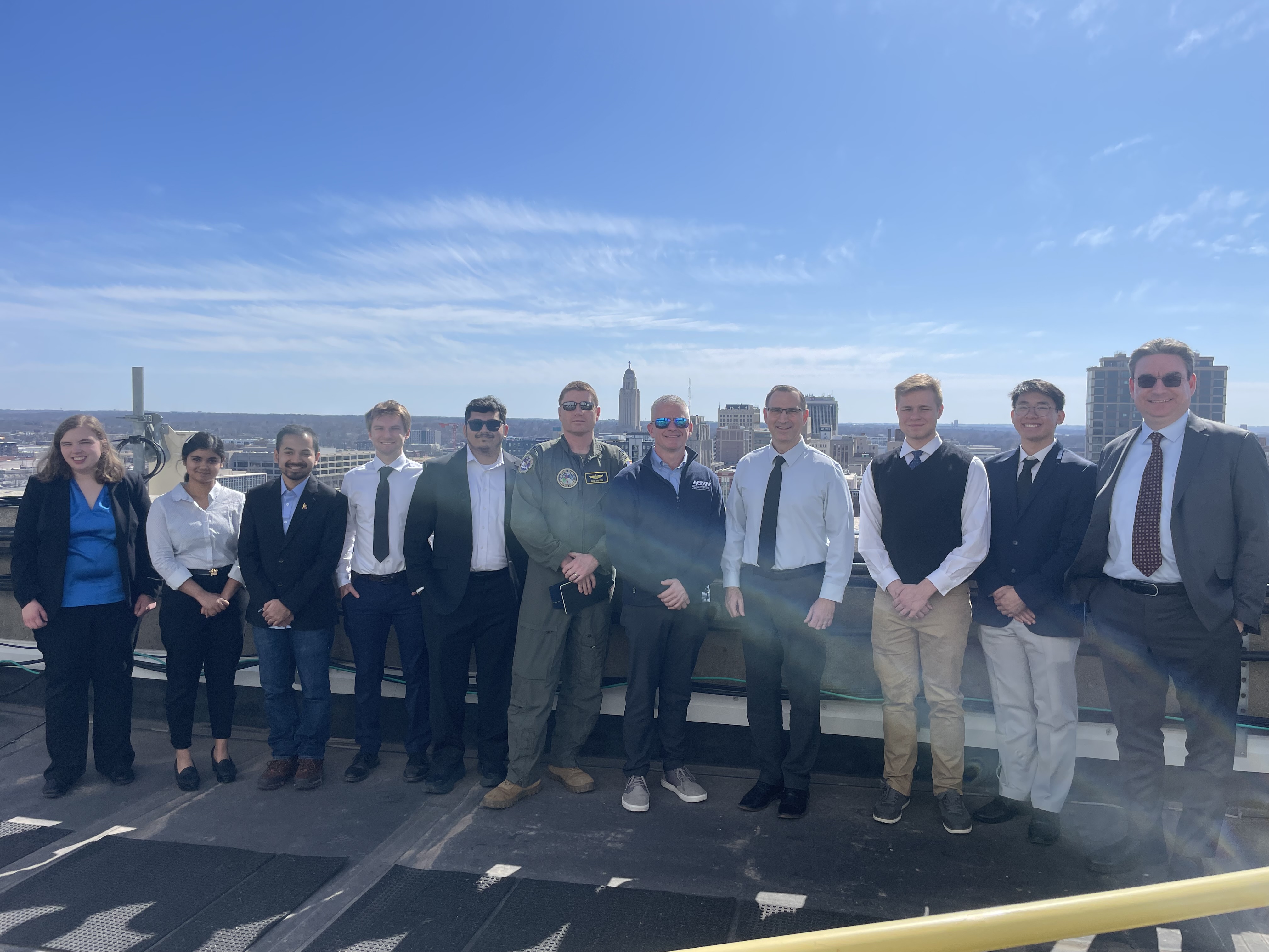 11 person research team lined up on a rooftop over looking Lincoln, NE